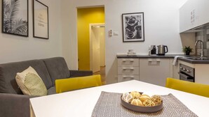 Un apartamento moderno con sala de estar, cocina y una mesa de comedor con un bol de pan.