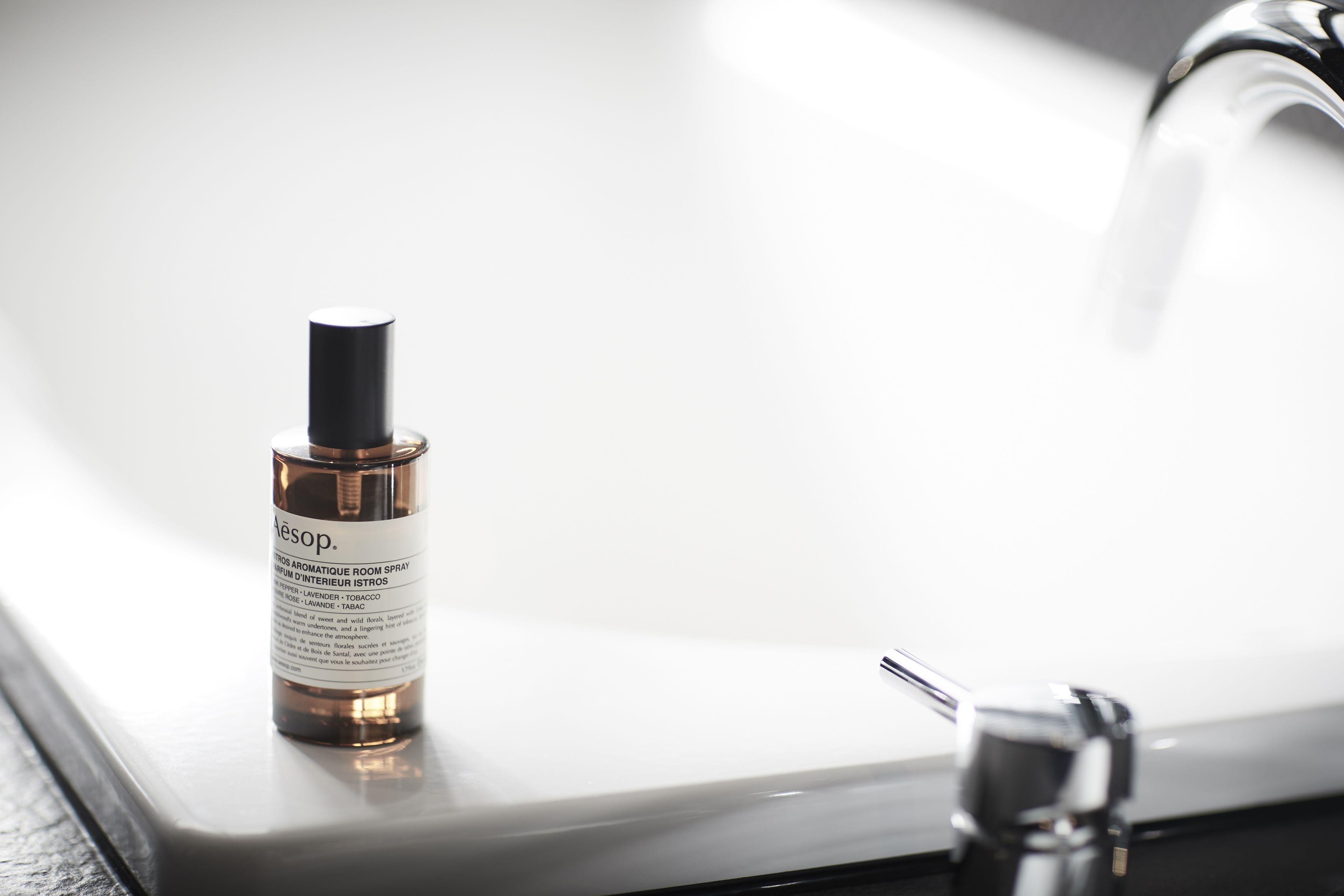A bottle of Aesop aromatique room spray on a bathroom sink.