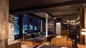 A modern interior with a stone accent wall, a sectional sofa, wooden furniture, and a bar area. - The Tower Hotel Nagoya (Nagoya)