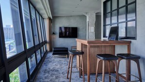 A modern bar area with a large TV, wooden bar counter, and black leather stools. - The Tower Hotel Nagoya (Nagoya)