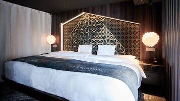 A modern hotel room with a geometric-patterned headboard, a large bed with white linens, and two bedside lamps.