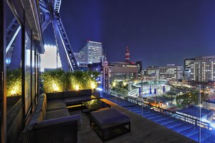 A rooftop terrace with seating, a view of the cityscape, and a crane structure.