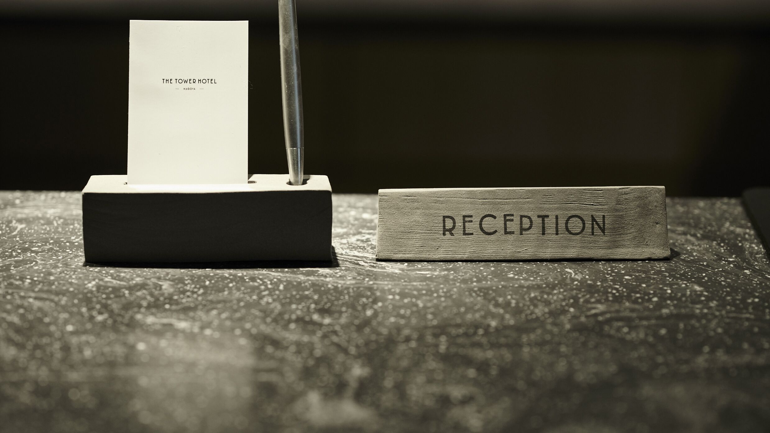 A reception desk with a sign labeled "RECEPTION" and a card holder with "THE TOWER HOTEL" written on it.
