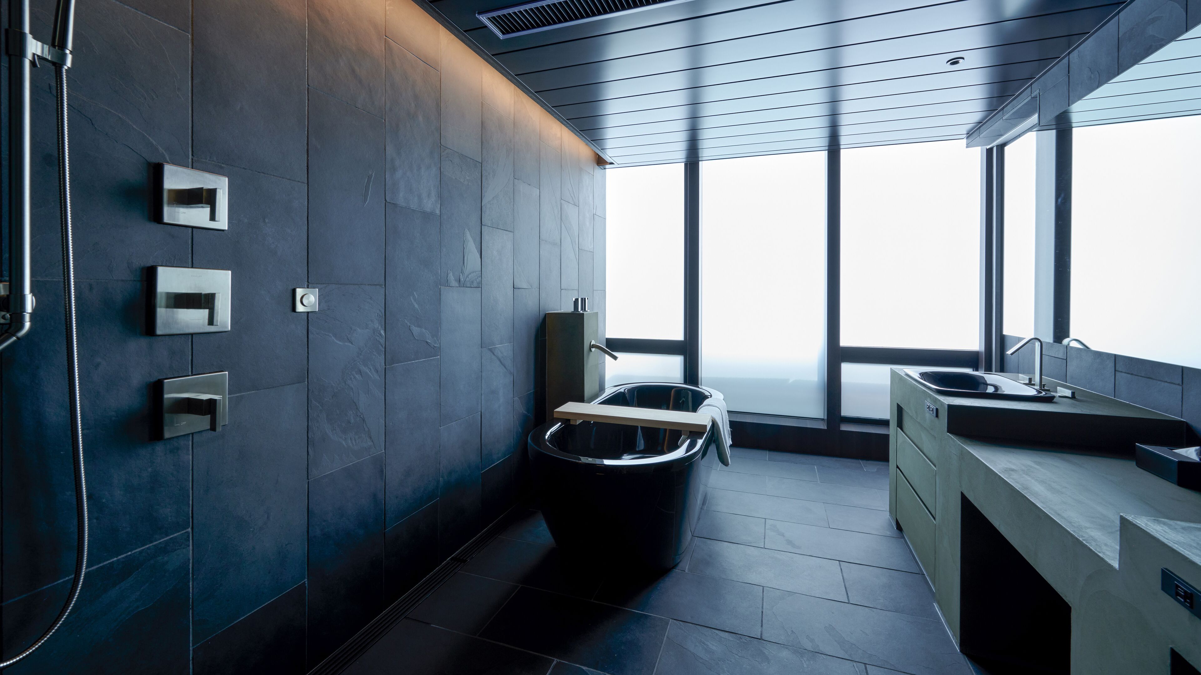 A modern bathroom with a large window, a built-in sink, and a shower area.