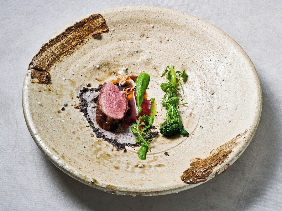 Ein runder Teller mit Fleisch, Gemüse und Soße.