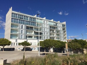 Um edifício moderno de vários andares, com varandas e grandes janelas.