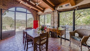 Un comedor con una mesa de madera, sillas y un refrigerador rojo. Se aprecia un amplio ventanal de arco que ofrece vistas del paisaje.