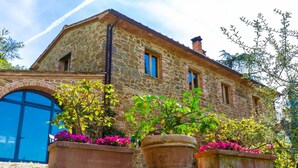 Un edificio de piedra con puerta azul, ventanas grandes y macetas con flores.