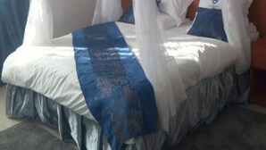 A bed with a canopy, pillows, and a blue decorative cloth. - Makindu Diamond Hotel (Makindu)