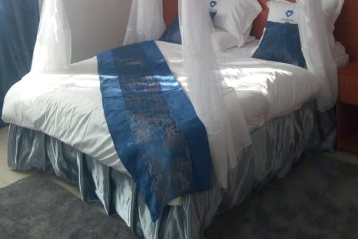 A bed with a canopy, pillows, and a blue decorative cloth.