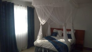 Ein Schlafzimmer mit einem Himmelbett, weißer Bettwäsche und einer blau-weißen Tagesdecke.