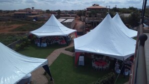 A view of a courtyard with white tents set up for an event, surrounded by buildings and greenery. - Makindu Diamond Hotel (Makindu)