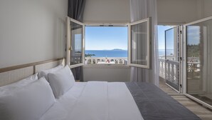 A hotel room with a large bed, a view of the sea, and a balcony with a railing. - Casa Panorama Adults Only (Sithonia)