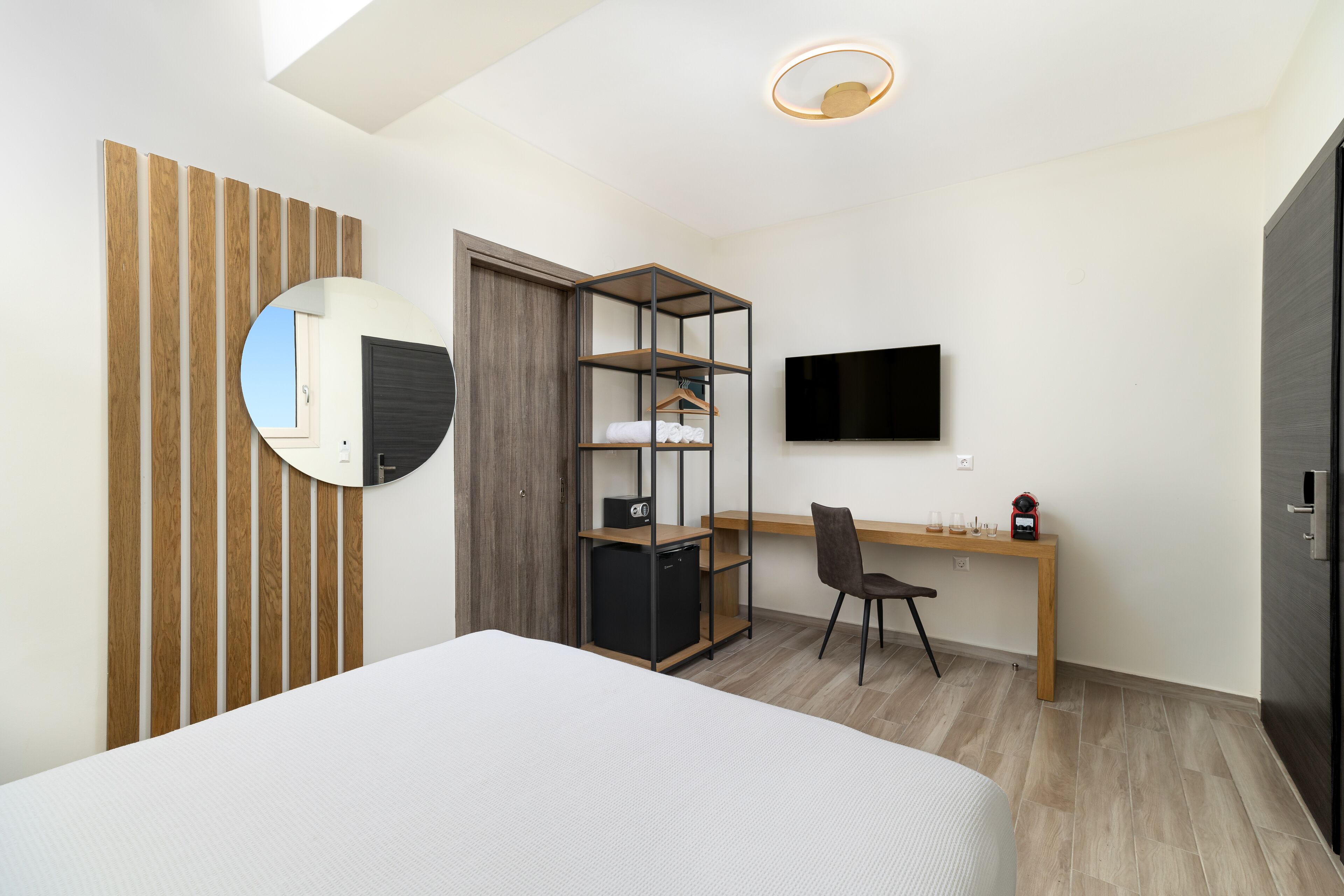 Un dormitorio con cama, escritorio, silla, armario, televisor y espejo.