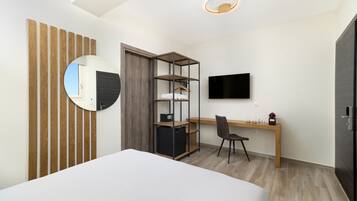 Un dormitorio con cama, escritorio, silla, armario, televisor y espejo.