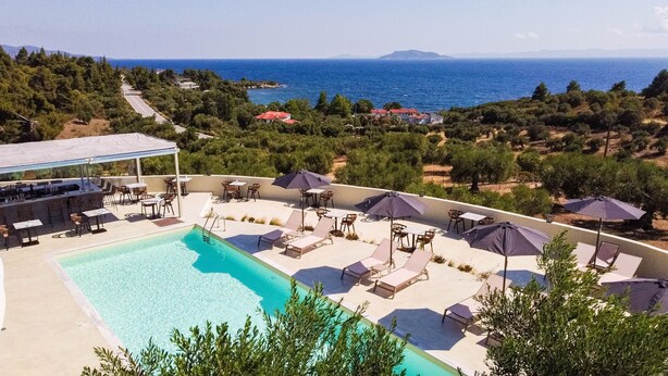 A pool area with lounge chairs and umbrellas, overlooking a scenic view of the sea and hills. - Casa Panorama Adults Only (Sithonia)