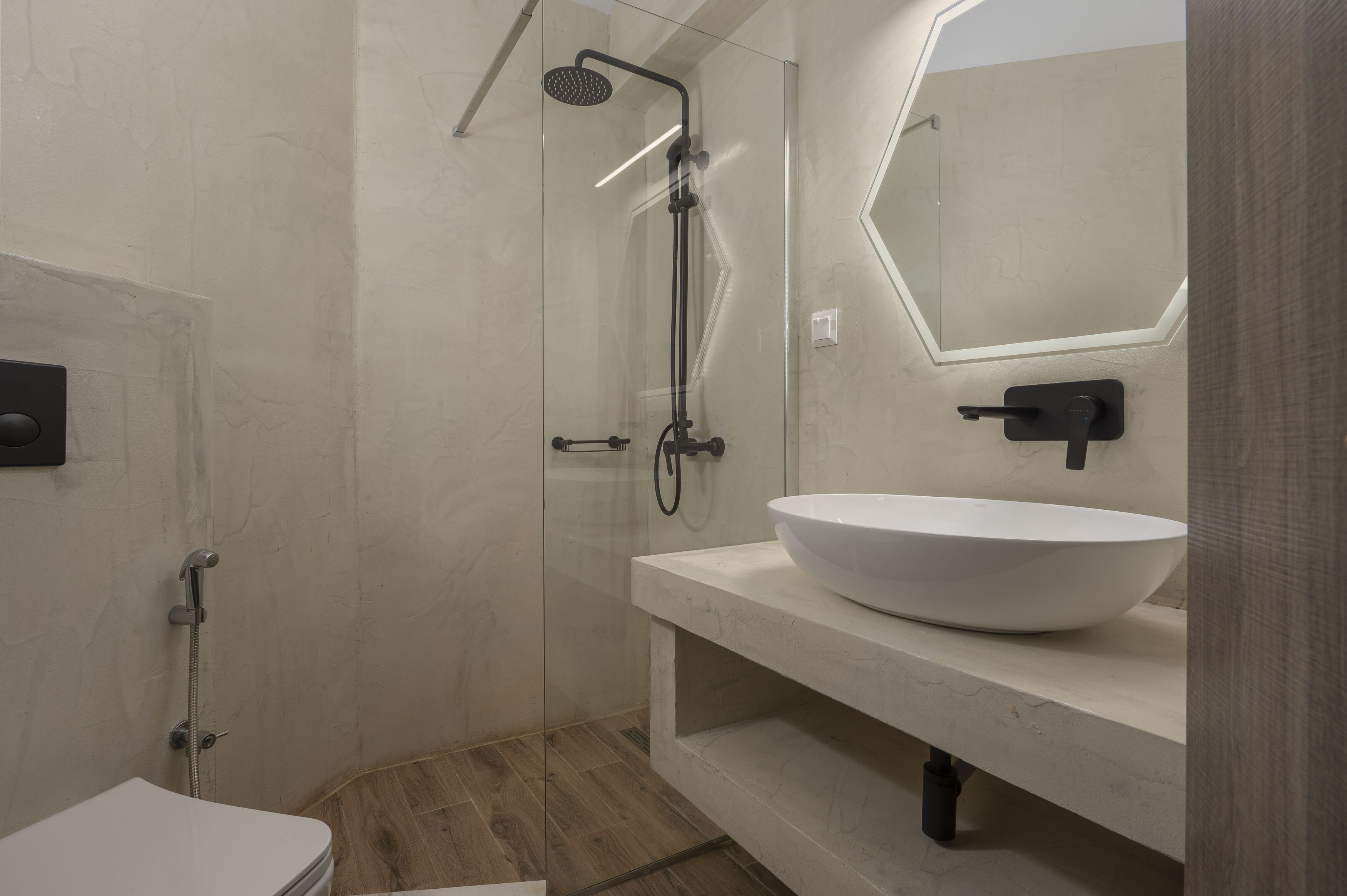A modern bathroom with a glass-enclosed shower, a white sink, and a large mirror.