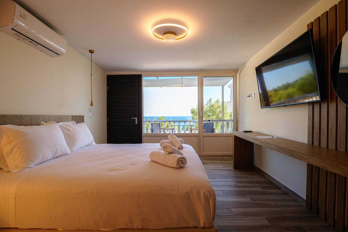 Une chambre d’hôtel avec un lit, une télévision et un balcon offrant une vue.