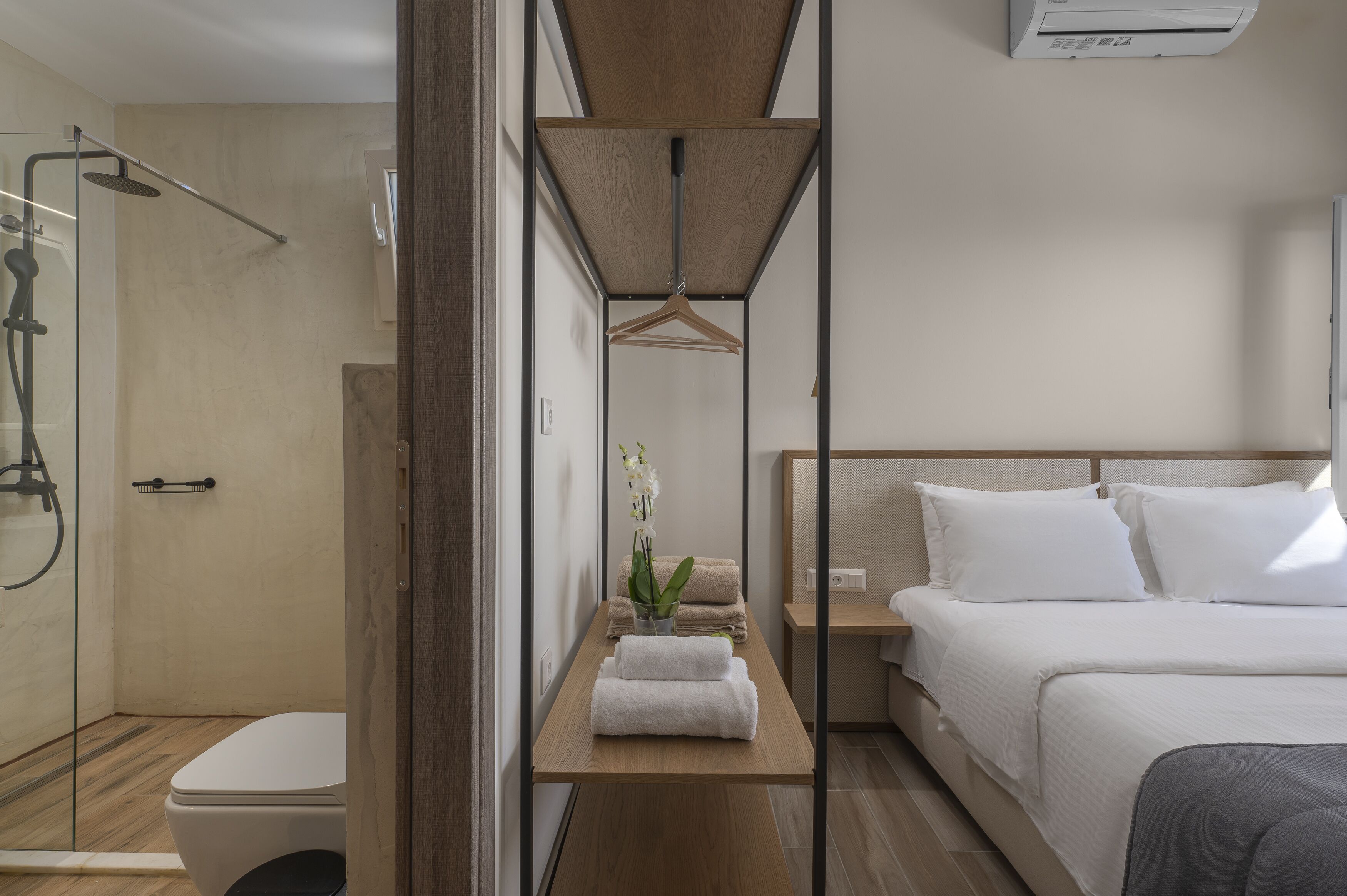 A modern hotel room with a shower, toilet, and a bed with white linens.