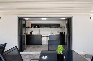 Une cuisine moderne avec des meubles de couleur sombre, un îlot central et un coin repas comprenant une table et des chaises.