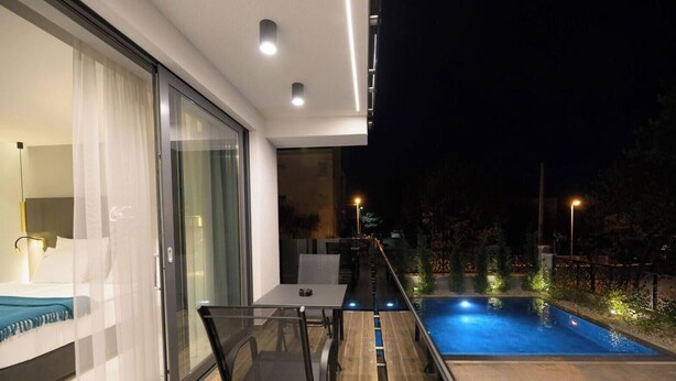 Un balcon extérieur moderne, doté d’une table et de chaises en verre, d’une piscine et d’un coin repas avec une table et des chaises.