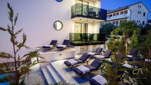 A modern villa with a pool area, outdoor seating, and a balcony.