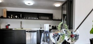 Eine moderne Küche mit schwarzem Arbeitsplatz, einer Gin-Flasche und zwei Gläsern mit Trinkhalm und Dekoration.