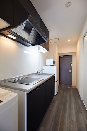 Een koelkast, een magnetron, een kookplaat, kookgerei, borden en bestek