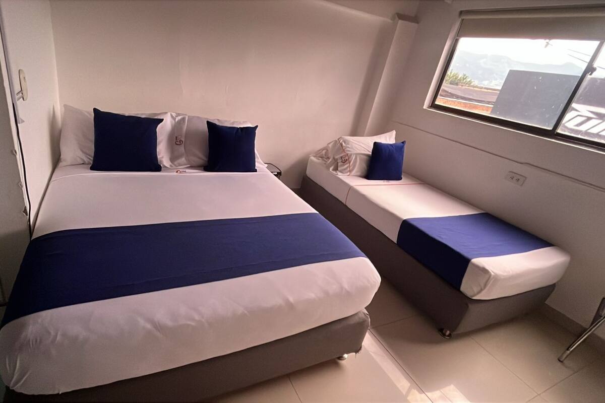 Un dormitorio con una cama grande, una cama más pequeña y un banco.