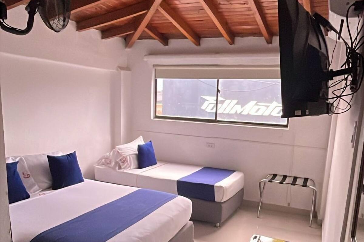 Habitación de hotel con dos camas, una mesita, un televisor y una ventana con vistas.