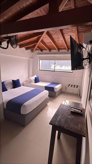 Una camera d'albergo con due letti, un tavolino, una televisione e una finestra con vista.