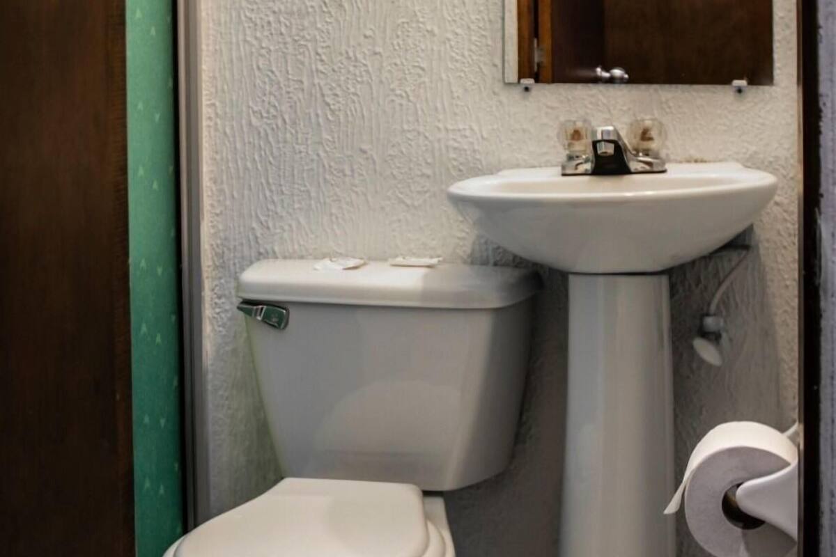 Un baño pequeño con inodoro, lavamanos y espejo.