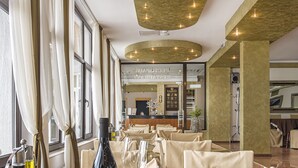 Interior de restaurante com mesas preparadas para refeições, uma garrafa de vinho e uma vela sobre a mesa.