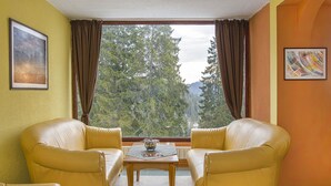 Um quarto com dois sofás de couro amarelo, uma mesa de madeira pequena e uma janela grande com cortinas.