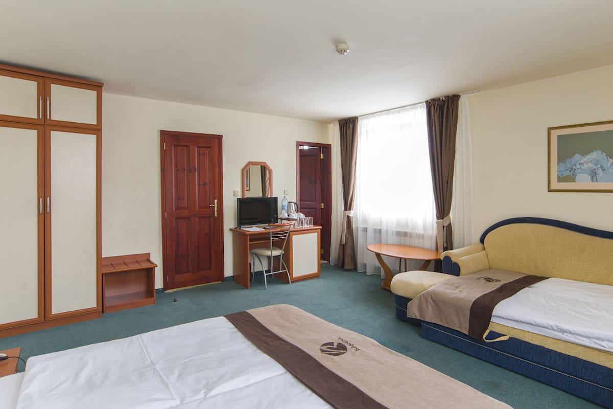 Hotelkamer met twee bedden, een bureau met computer, een stoel, een kledingkast en een schilderij aan de muur.