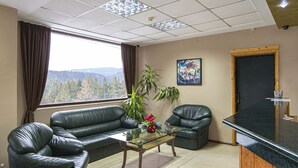 Uma sala de estar moderna com sofás de couro, uma mesa de centro de vidro e vista para montanhas pela janela.
