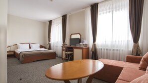 Quarto de hotel com cama, escrivaninha, cadeira e uma mesa redonda.