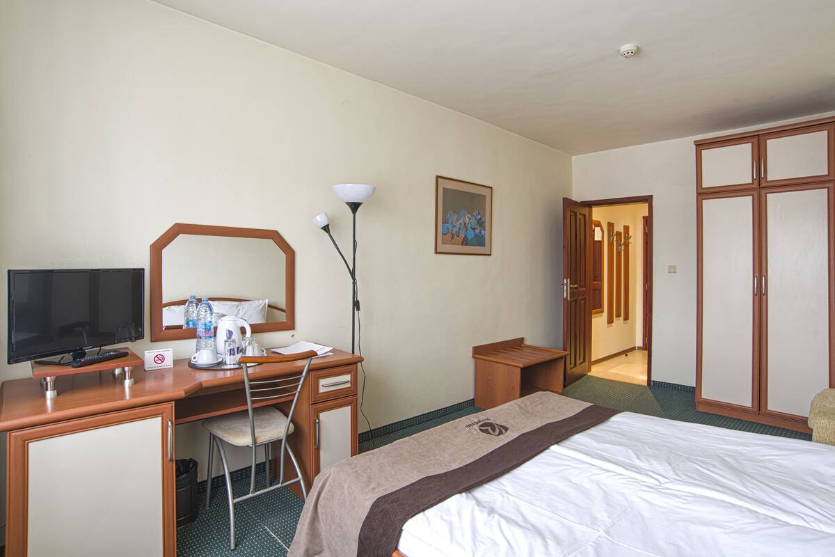 Een hotelkamer met een bed, bureau, stoel, televisie en een kledingkast.