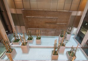 Ein moderner Innenhof mit einer zentralen Wasserspiele-Anlage, umgeben von Pflanzgefäßen mit Bambuspflanzen.