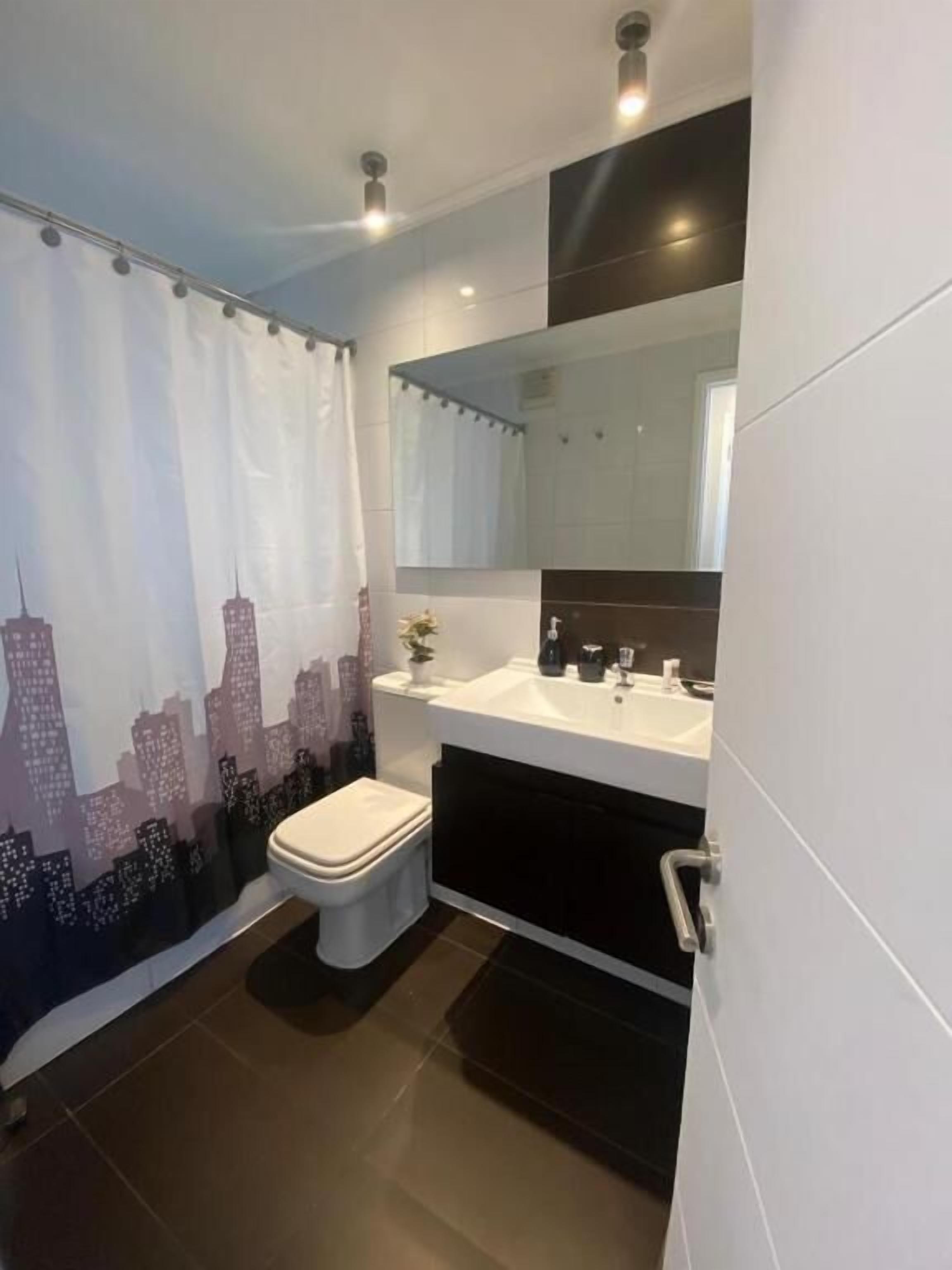 Ein modernes Badezimmer mit Toilette, Waschbecken und Spiegel.