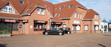 A brick building with multiple storefronts, including a 'BIG STAR' restaurant. There are two cars parked in front.