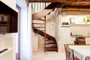 A kitchen with a stone wall, wooden staircase, and a clock on the wall. - Authentic Villa surrounded by Nature CIN IT055032C29Z019674 (Terni, Fraz. Torre Orsina)