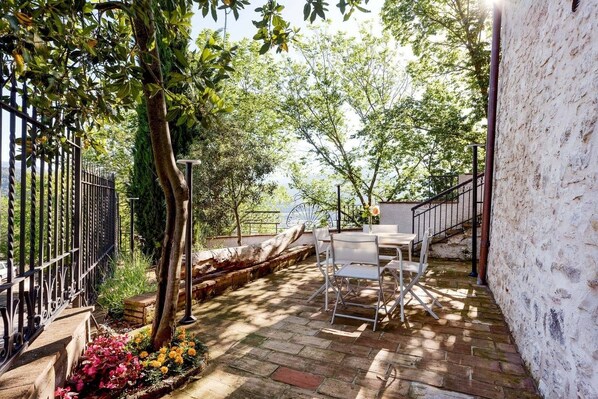An outdoor patio with a table and chairs, surrounded by a stone wall and a metal fence. - Authentic Villa surrounded by Nature CIN IT055032C29Z019674 (Terni, Fraz. Torre Orsina)