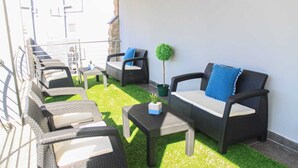 A terrace with outdoor furniture, a small table, and a potted plant. - The Cato Suites Hotel (Durban)