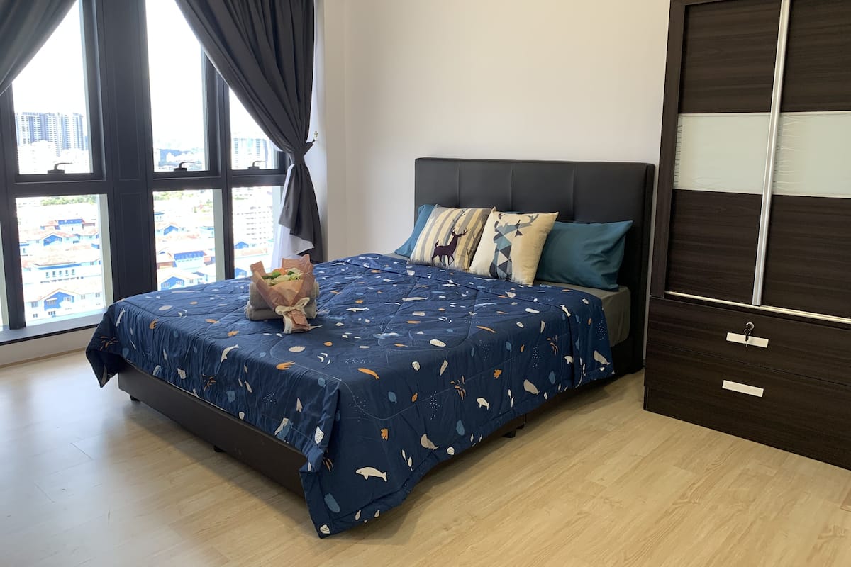 Ein Schlafzimmer mit einem Bett, einem Nachttisch, einer Kommode und einem Fenster mit Vorhängen.