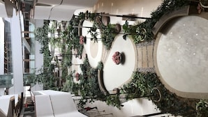 A modern atrium with a central circular seating area surrounded by lush greenery and potted plants.