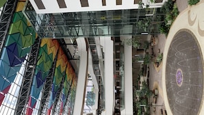 A multi-level atrium with glass railings, a central staircase, and a circular decorative element.