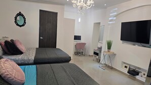 Ein modernes Schlafzimmer mit Bett, Schreibtisch, Stuhl, Fernseher und einer Kristallleuchter.