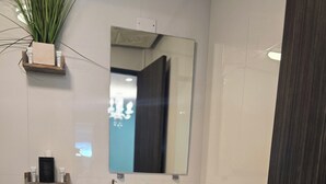 Ein Badezimmer mit Toilette, Waschbecken, Spiegel und einer Pflanze auf einem Regal.