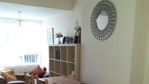 A dining area with a wooden table and chairs, a bookshelf, and a decorative mirror on the wall. - Family holiday home near both sea front and town (Yarmouth)